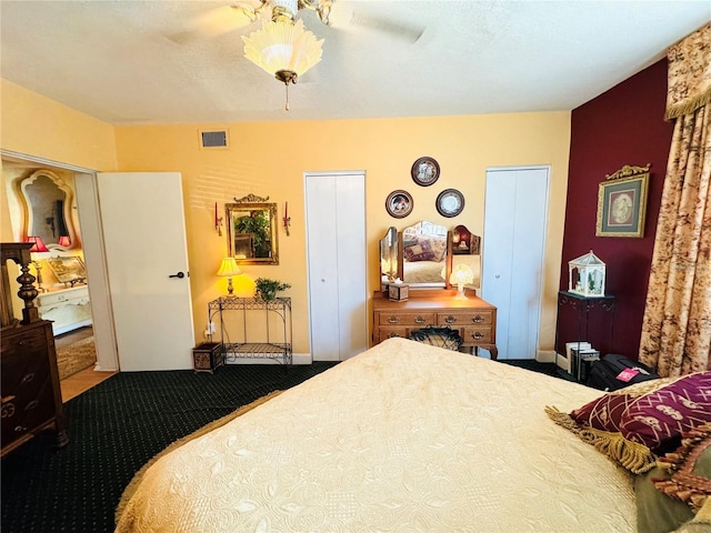 carpeted bedroom with two closets and ceiling fan