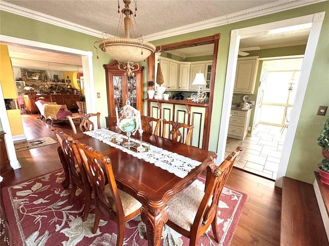 dining area featuring a textured ceiling, wood finished floors, and crown molding