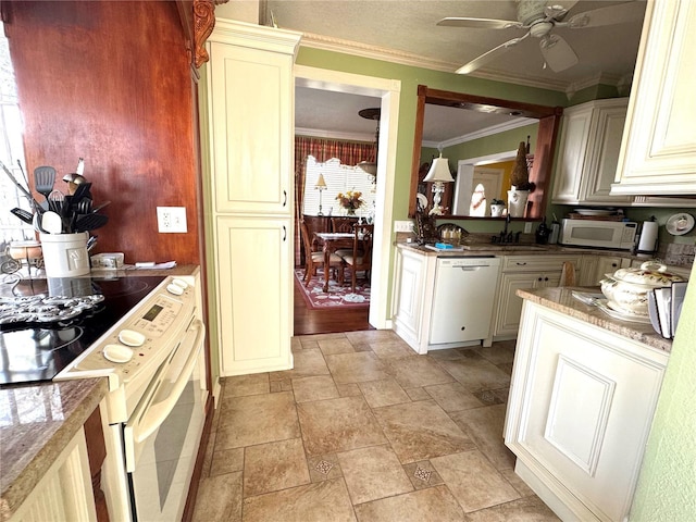 kitchen with cream cabinets, ornamental molding, a ceiling fan, stone finish floor, and white appliances