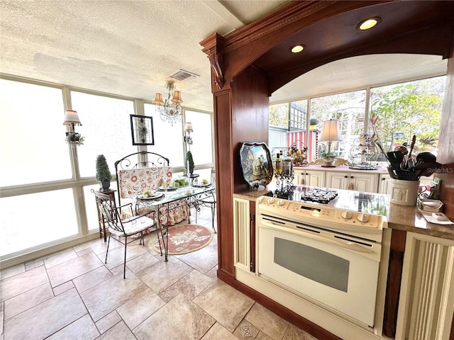 kitchen with electric stove, cream cabinetry, light countertops, visible vents, and a textured ceiling