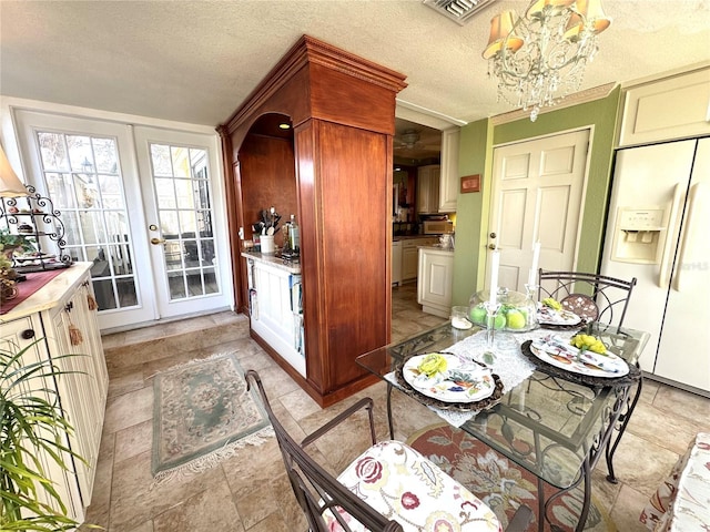 dining room with french doors, visible vents, a notable chandelier, and a textured ceiling