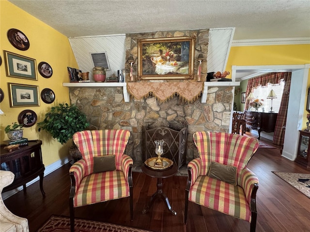 living area featuring dark wood-type flooring, a stone fireplace, a textured ceiling, and baseboards