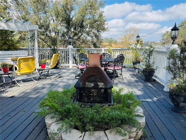 wooden terrace featuring an outdoor fire pit, outdoor dining area, and a pergola