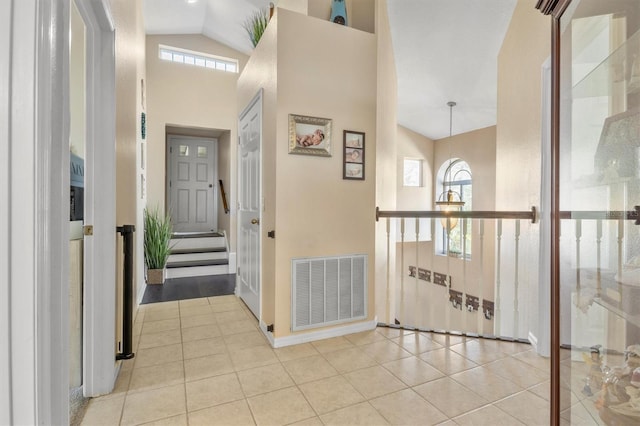 corridor featuring high vaulted ceiling and light tile patterned floors