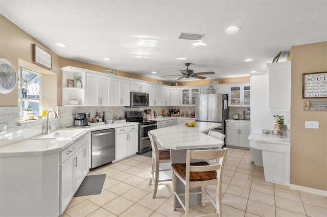 kitchen with white cabinetry, stainless steel appliances, light tile patterned floors, and sink