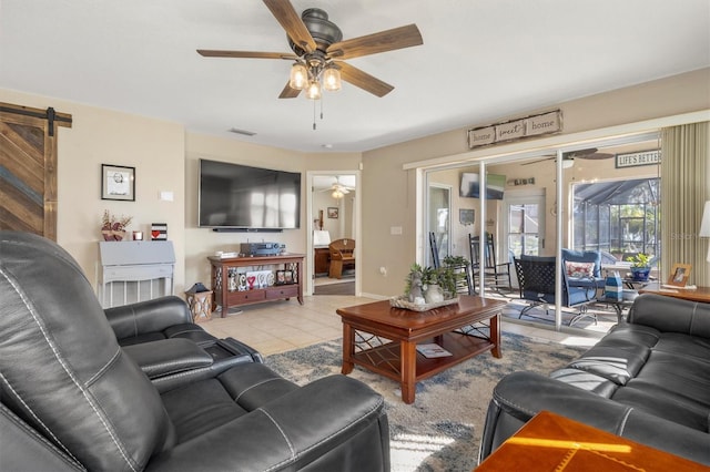 tiled living room featuring ceiling fan and a barn door