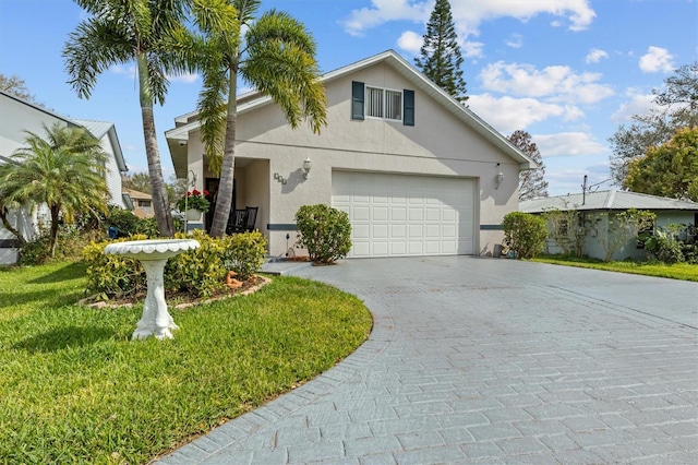 view of front of property with a front lawn, decorative driveway, an attached garage, and stucco siding