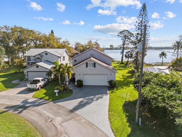 view of front of home featuring a garage, driveway, a front lawn, and a water view