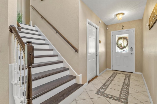 foyer featuring tile patterned floors, baseboards, and stairs