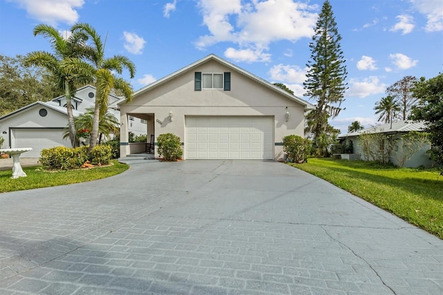 view of front of house featuring stucco siding, a front lawn, a garage, and driveway