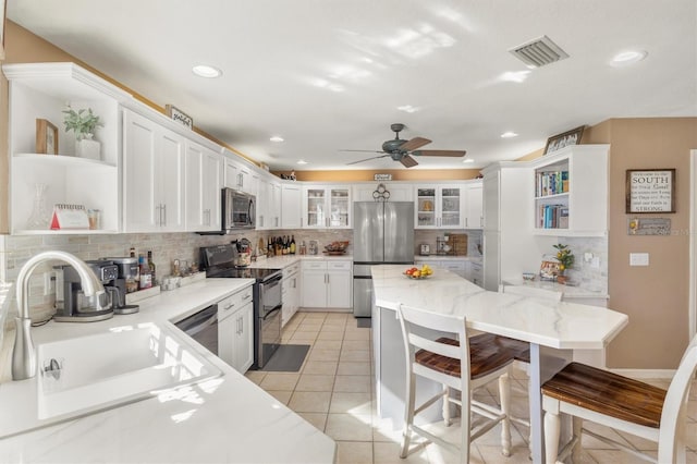 kitchen featuring open shelves, visible vents, appliances with stainless steel finishes, and a sink