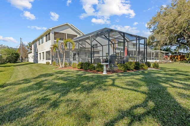 back of property with glass enclosure and a lawn