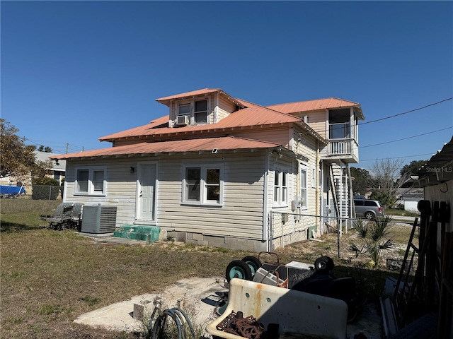 rear view of property featuring central AC unit and a lawn