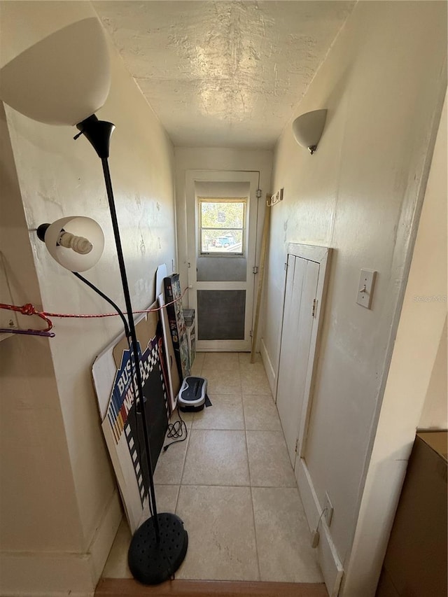 hall featuring light tile patterned floors and a textured ceiling