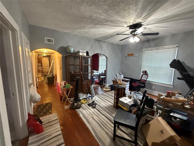 misc room with hardwood / wood-style flooring, ceiling fan, and a textured ceiling