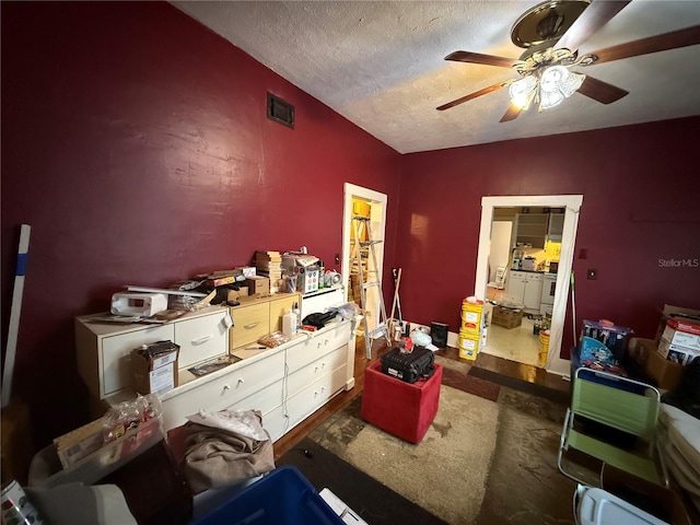 miscellaneous room with ceiling fan and a textured ceiling