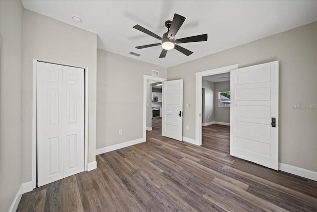 unfurnished bedroom with dark wood-type flooring, ceiling fan, and a closet