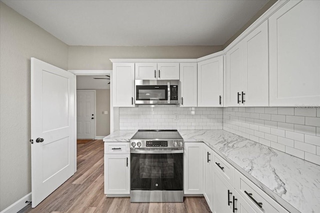 kitchen featuring white cabinetry, appliances with stainless steel finishes, light hardwood / wood-style flooring, and backsplash