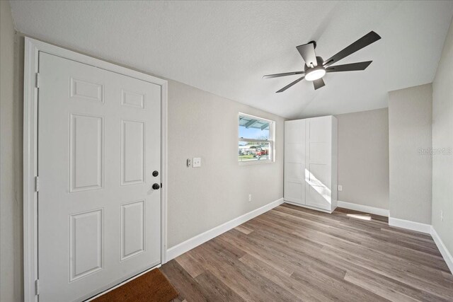 foyer featuring ceiling fan, lofted ceiling, light hardwood / wood-style floors, and a textured ceiling