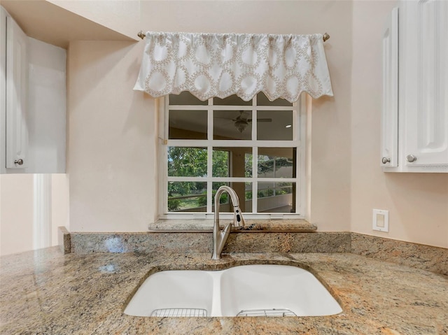 room details featuring white cabinetry, sink, and light stone countertops