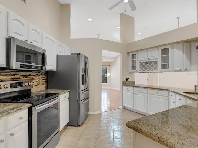 kitchen featuring white cabinetry, appliances with stainless steel finishes, light stone counters, and backsplash