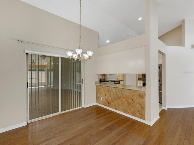 kitchen featuring sink, high vaulted ceiling, dark hardwood / wood-style floors, a notable chandelier, and decorative light fixtures