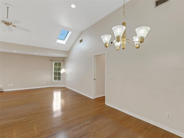 spare room featuring hardwood / wood-style flooring, ceiling fan with notable chandelier, a skylight, and high vaulted ceiling