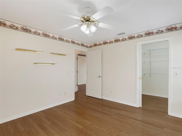 unfurnished bedroom with hardwood / wood-style flooring, ceiling fan, a spacious closet, and a closet