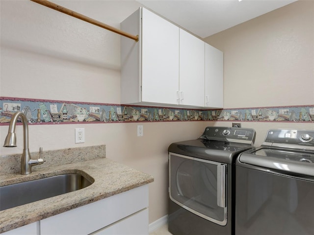 clothes washing area featuring sink, cabinets, and washing machine and clothes dryer