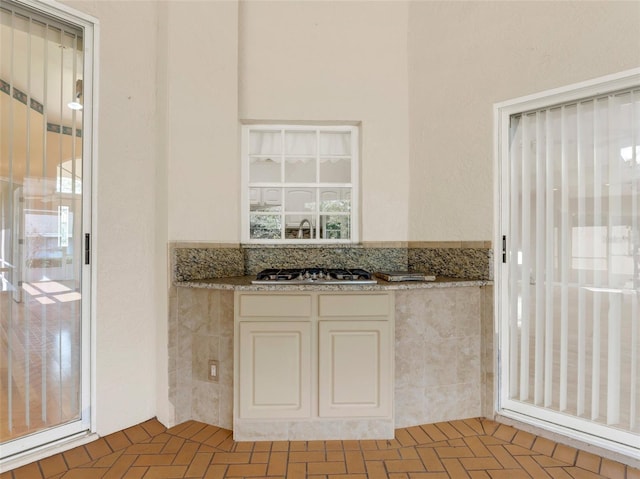 kitchen featuring stainless steel gas stovetop, white cabinetry, and stone counters