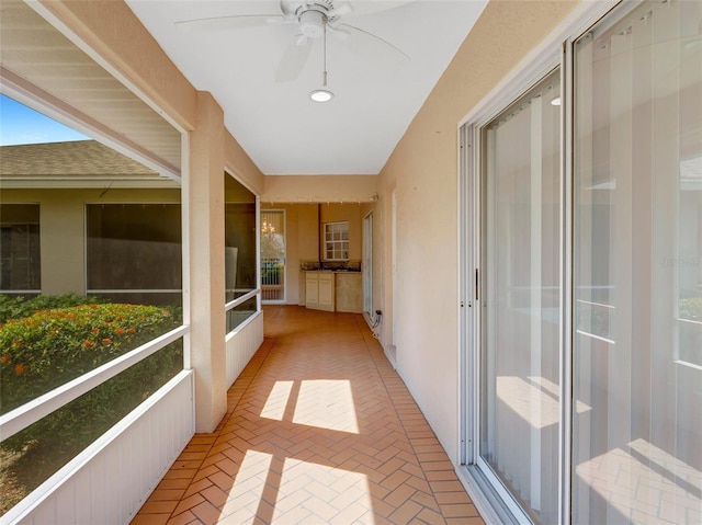 unfurnished sunroom featuring ceiling fan