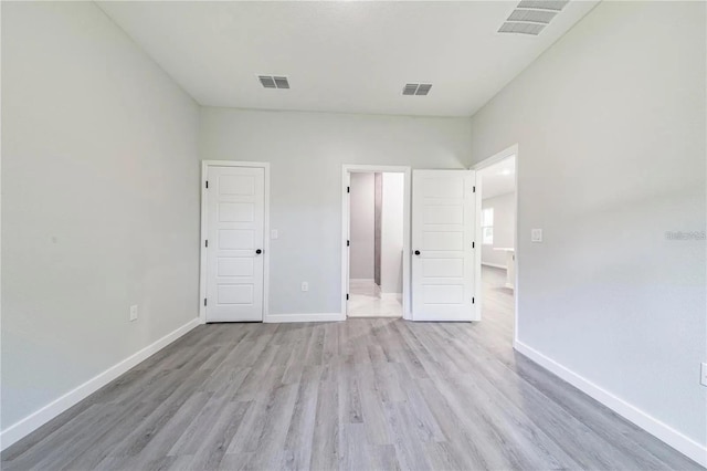 unfurnished bedroom with wood finished floors, baseboards, and visible vents