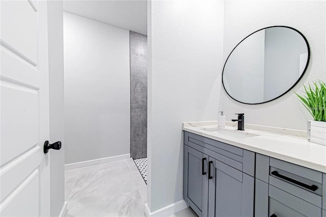 full bathroom featuring a tile shower, marble finish floor, vanity, and baseboards