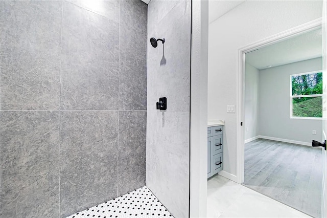 bathroom featuring vanity, baseboards, and tiled shower