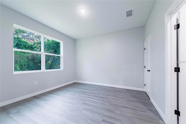 unfurnished room with wood finished floors, visible vents, and baseboards