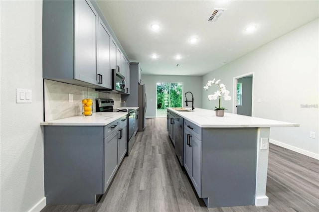 kitchen with tasteful backsplash, gray cabinetry, visible vents, and stainless steel appliances