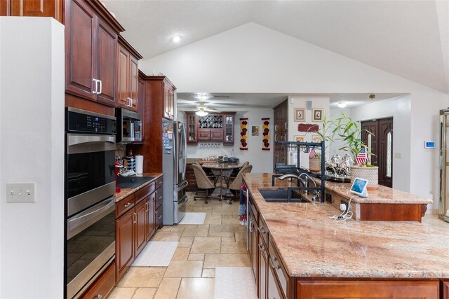 kitchen with ceiling fan, an island with sink, appliances with stainless steel finishes, and sink