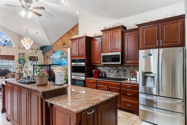 kitchen featuring appliances with stainless steel finishes, a center island, tasteful backsplash, ceiling fan with notable chandelier, and vaulted ceiling