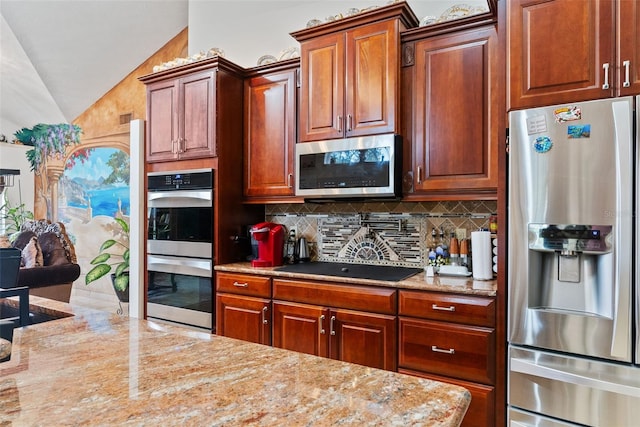 kitchen featuring light stone counters, vaulted ceiling, stainless steel appliances, and tasteful backsplash