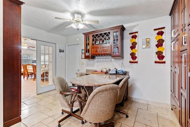 dining room featuring ceiling fan, bar, a textured ceiling, and french doors