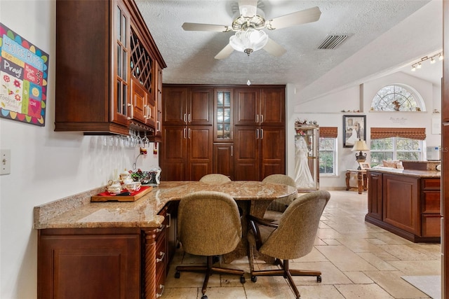 dining room featuring ceiling fan, built in desk, vaulted ceiling, and a textured ceiling