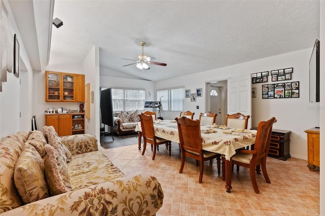 dining space with lofted ceiling, ceiling fan, and a textured ceiling