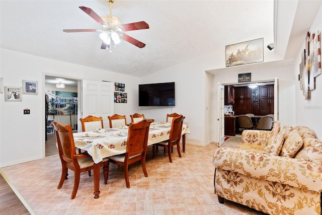 dining room with ceiling fan, vaulted ceiling, and a textured ceiling