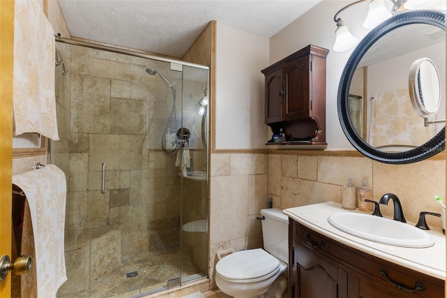 bathroom with tile walls, vanity, an enclosed shower, toilet, and a textured ceiling