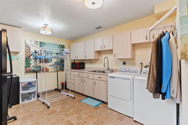 laundry room with sink, a textured ceiling, cabinets, and washing machine and clothes dryer