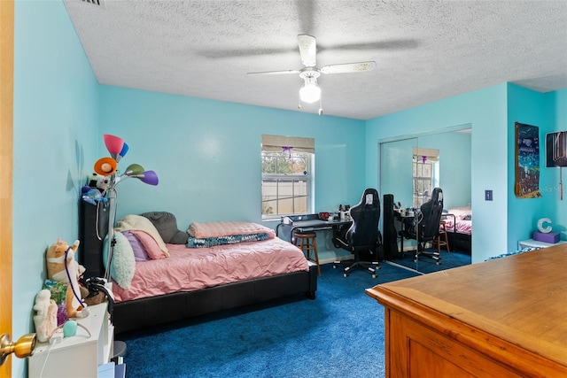 bedroom with a textured ceiling, a closet, ceiling fan, and dark colored carpet