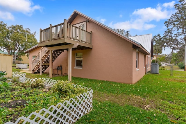 back of house featuring a wooden deck, a lawn, and central air condition unit