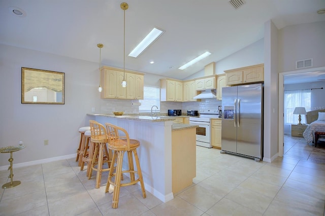 kitchen featuring white electric range, stainless steel fridge, light stone countertops, a kitchen bar, and kitchen peninsula