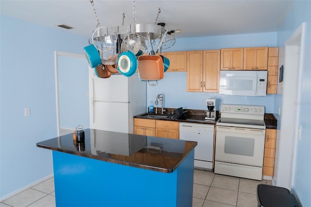 kitchen featuring light brown cabinetry, sink, a center island, light tile patterned floors, and white appliances