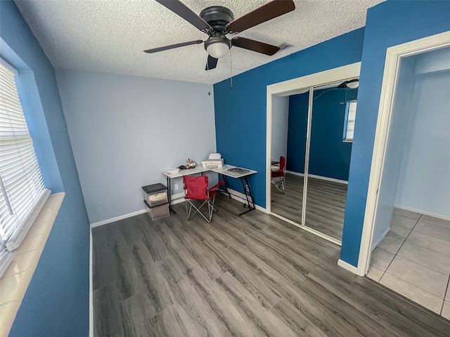 unfurnished office featuring ceiling fan, hardwood / wood-style floors, and a textured ceiling